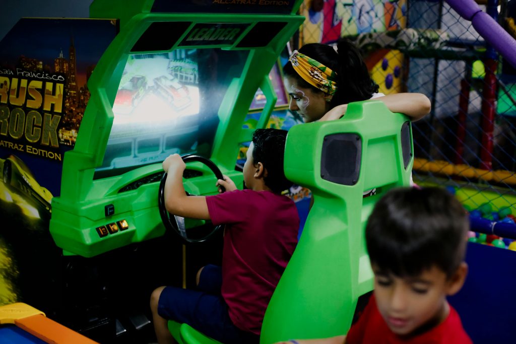 Kids enjoy a vibrant racing game simulator in an indoor play area, focusing on the screen.